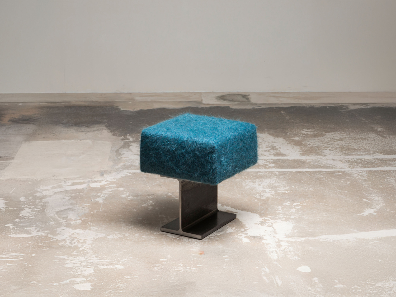 Low stool with a shaggy teal-blue mohair cushion set on a blackened steel I-beam base, on a raw concrete floor — Umberto Bellardi Ricci Trono