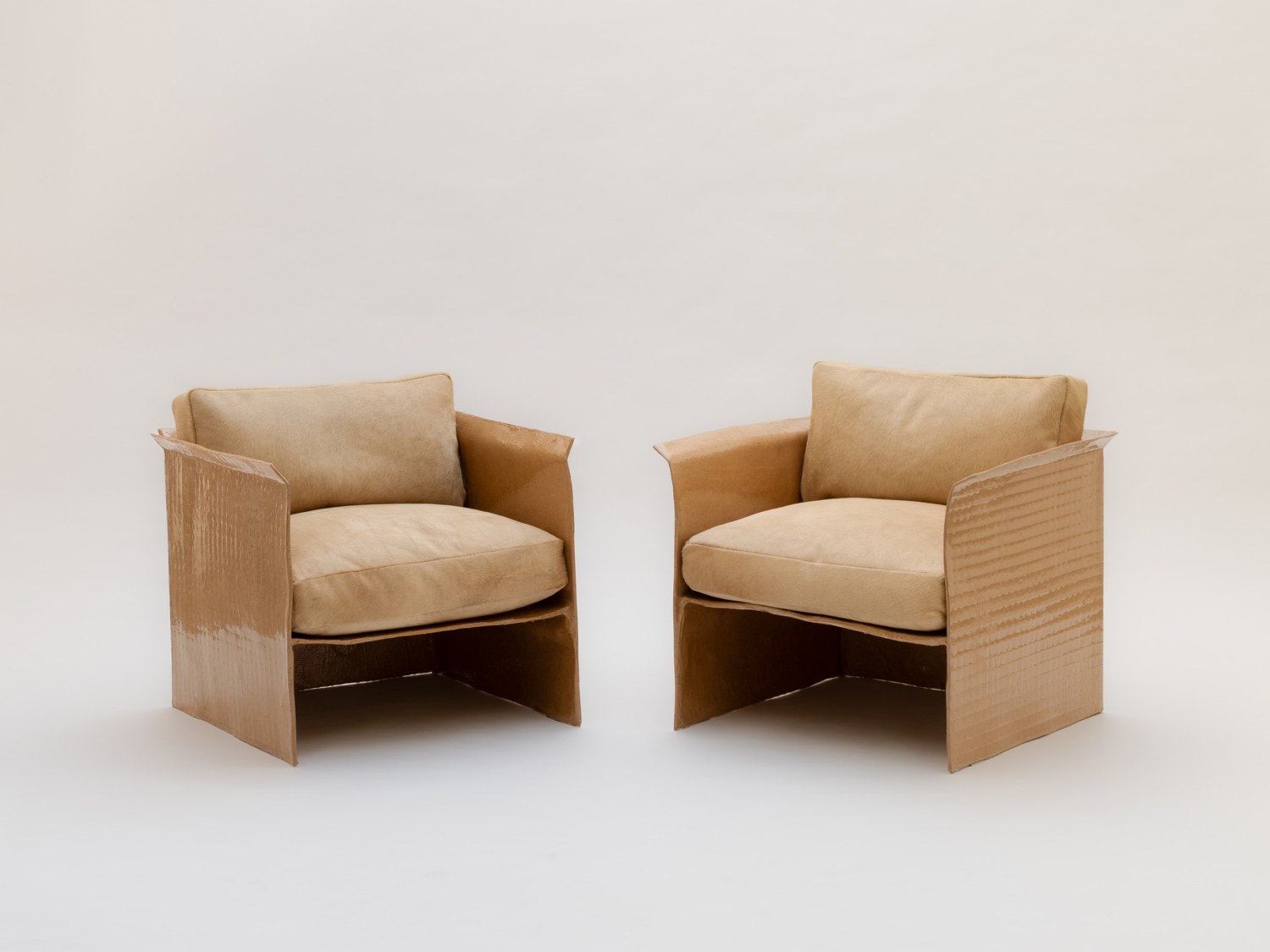 Pair of armchairs with textured tan hide upholstery, boxy panelled sides and loose cushioned seats and backs — Studio Haos Set of Fiberglass Armchairs