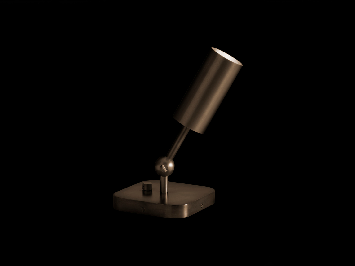 Angled brass cylinder uplight on a rounded-square base, tilting on a spherical knuckle joint against black — Apparatus Studio Cylinder Uplight