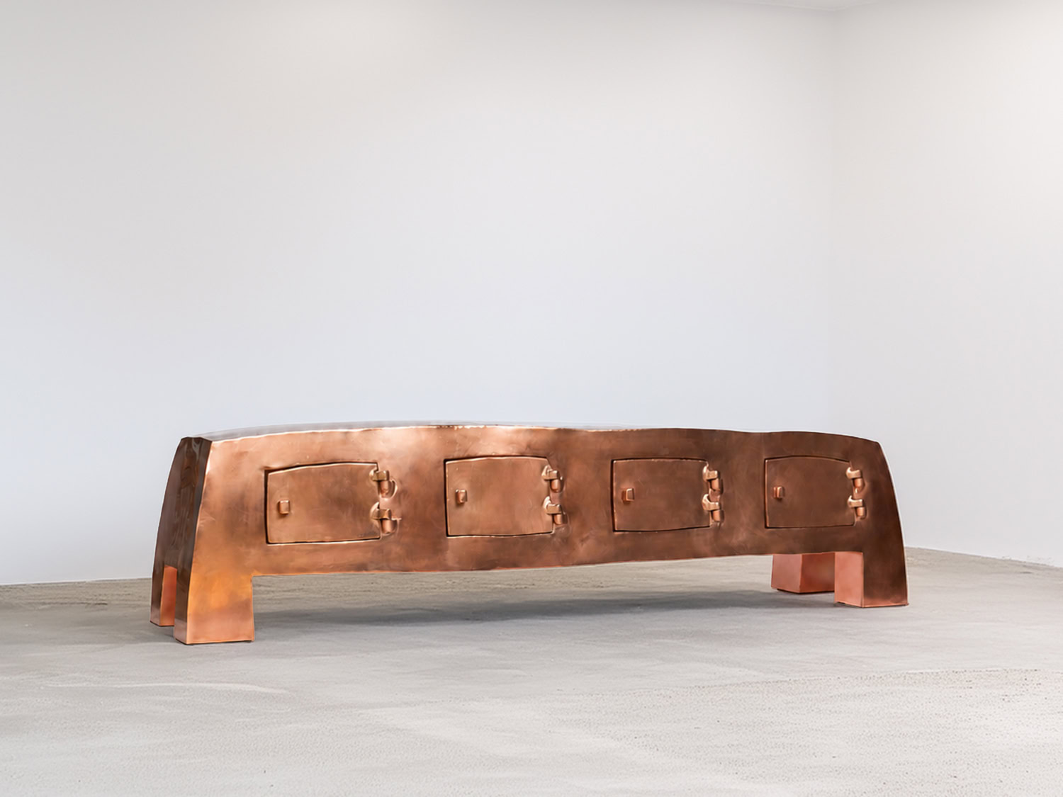 Long low credenza in polished copper with a curved silhouette, four recessed cabinet doors and sculptural clasp handles, on block feet — Nick Valentijn Long Low Credenza – Copper