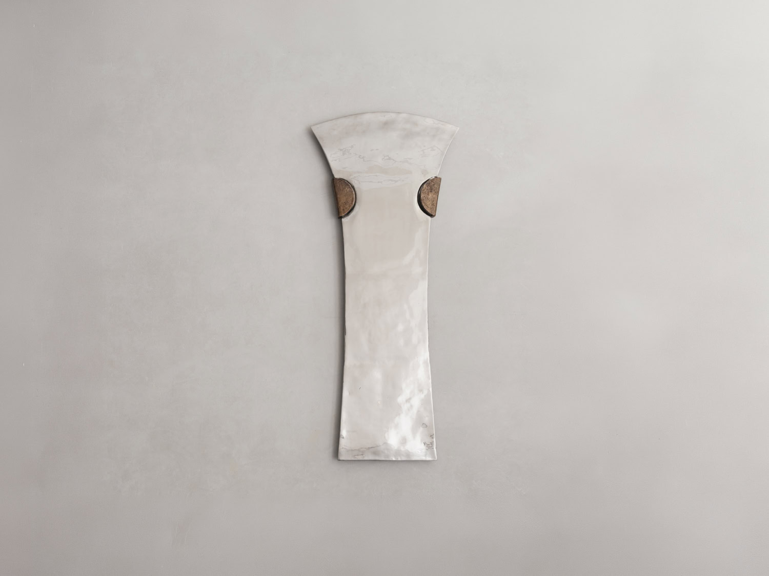 Wall mirror with elongated flared hourglass form in mottled polished silver, flanked by two aged bronze half-disc mounts — EWE Studio EXHUMA Mirror